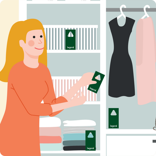 Frau mit roten Haaren platziert Legona Schlupfwespenkarten in einem Schrank mit Kleidung und Regalen mit gefalteten Textilien.