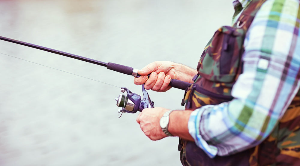 Nahaufnahme eines Anglers mit kariertem Hemd und Angelrute in den Händen