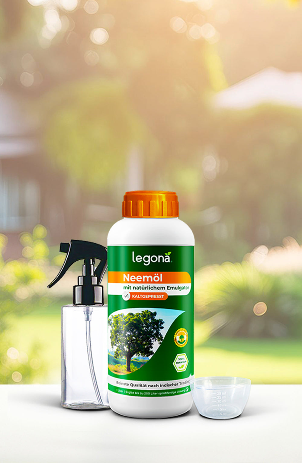 Legona Neemöl in weißer Flasche mit orangefarbenem Deckel, daneben eine Sprühflasche und ein Messbecher, im Hintergrund unscharfer Garten