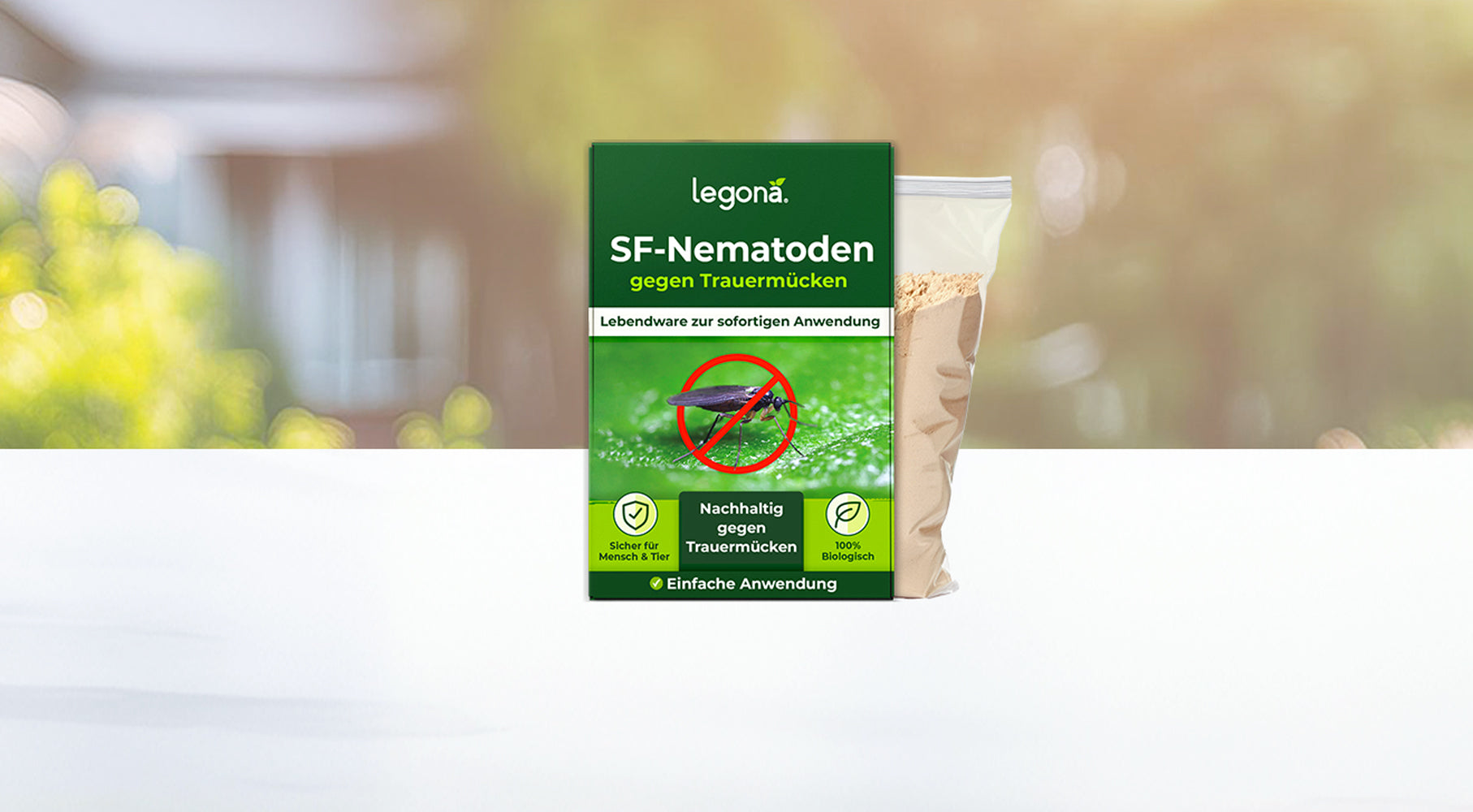 Verpackung von Legona SF-Nematoden gegen Trauermücken mit grünem Etikett und Symbolen für nachhaltige Anwendung und einfache Nutzung vor unscharfem Garten-Hintergrund