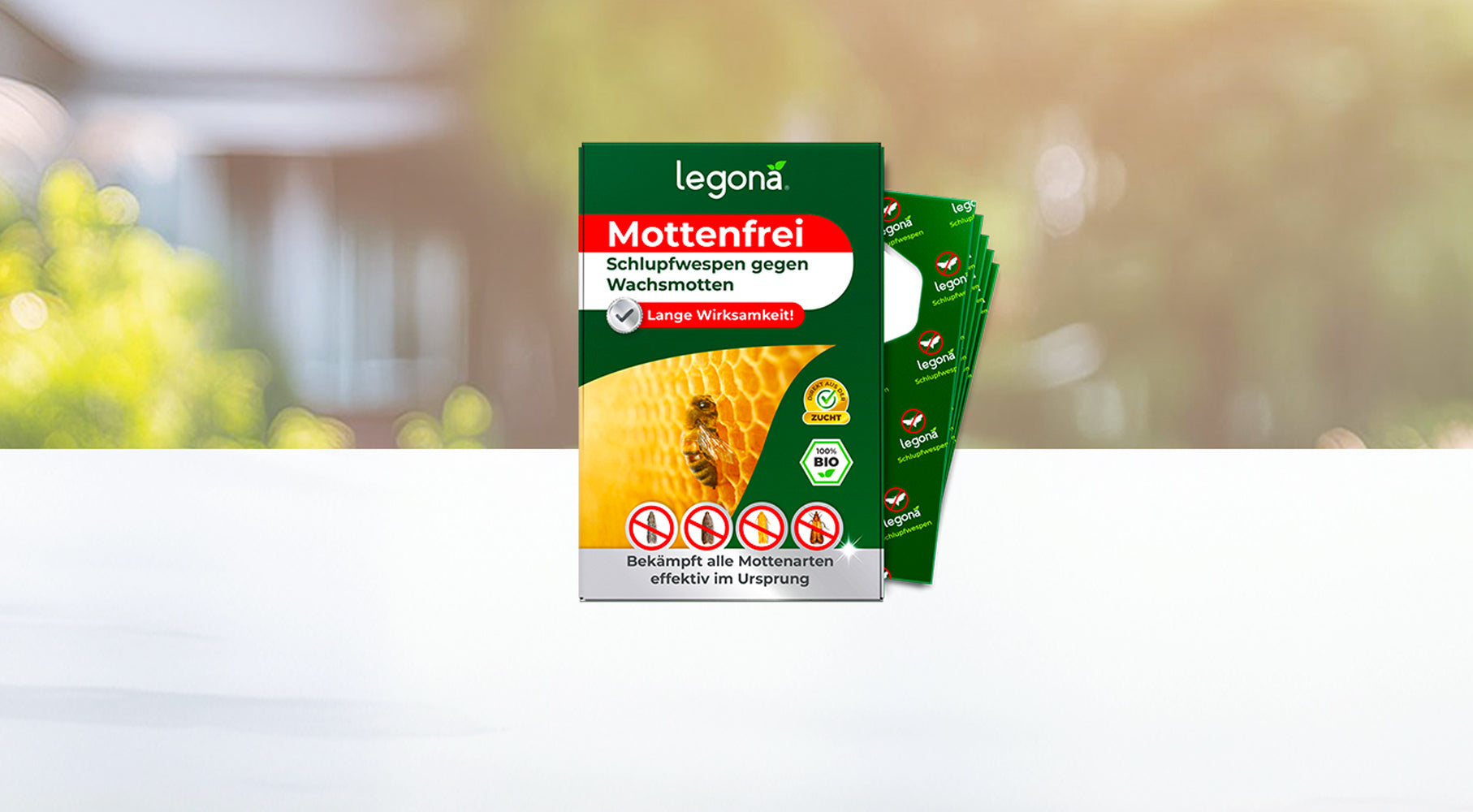 Verackung des Produkts 'Legona Mottenfrei' Schlupfwespen gegen Wachsmotten mit gelbem Wabenmuster vor unscharfem Garten-Hintergrund